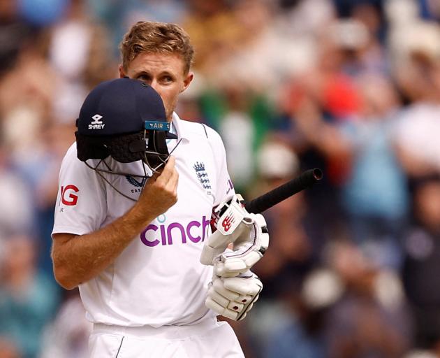 Joe Root kisses his helmet to celebrate reaching his century in the match against India at...