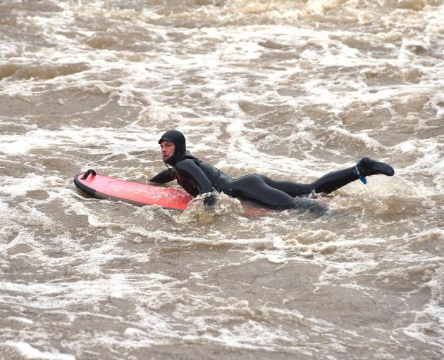 Surfer Toby Hille takes on the flooded Water of Leith yesterday. PHOTO: PETER MCINTOSH