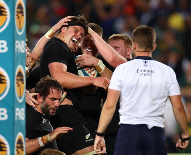 Scott Barrett celebrates with teammates after scoring the All Blacks' fourth try against South...