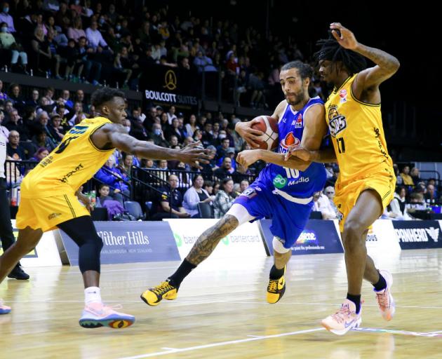 Saints star Xavier Cooks tries to beat Airs defenders Shaun Willett (left) and Javonte Douglas...