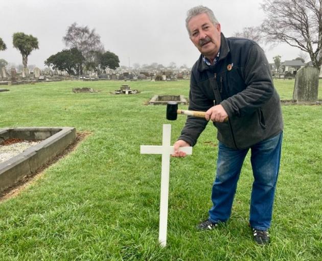 Terry McLaughlin places a makeshift cross on the unmarked grave of Gallipoli veteran Private...