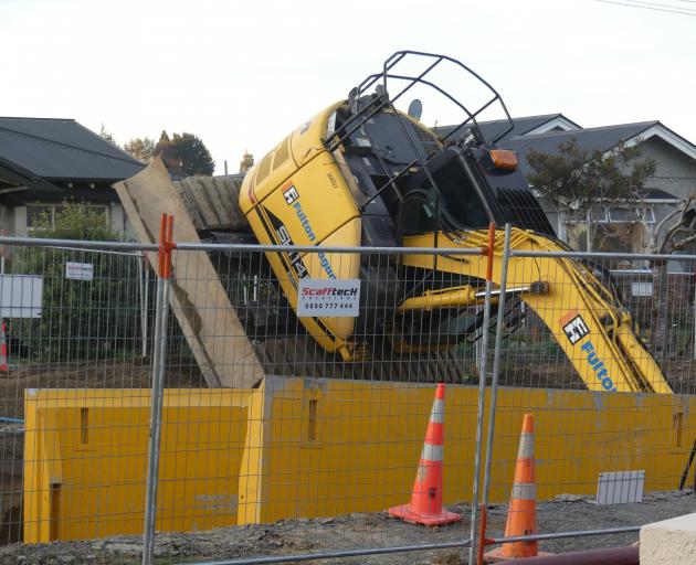 A Fulton Hogan excavator lies half inside the 5m trench it was digging in Elizabeth St, Gore,...