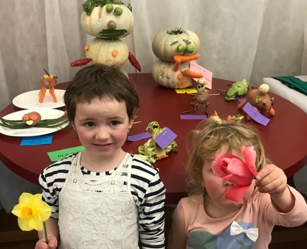Jess Bonner (4) holds a daffodil, while her sister, Laura (3), shyly hides behind a tulip. Behind...