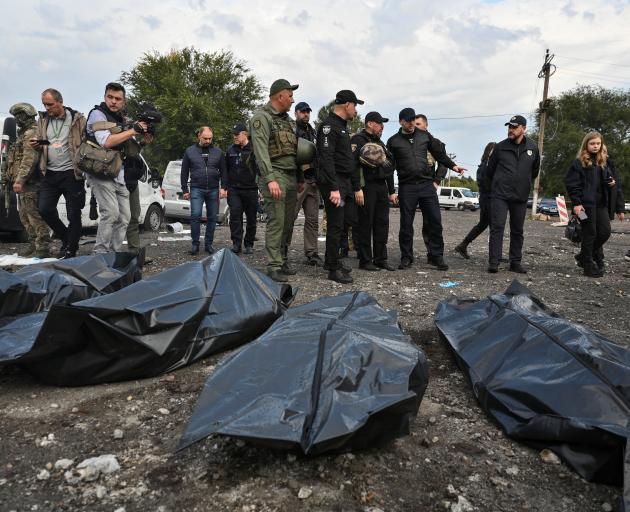 Ukrainian Interior Minister Denys Monastyrskyi stands next to the covered bodies of persons...