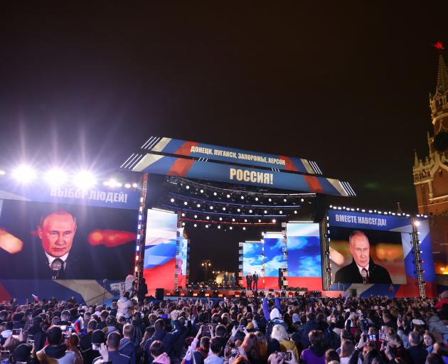 Spectators listen to Russian President Vladimir Putin during a concert marking the declared...