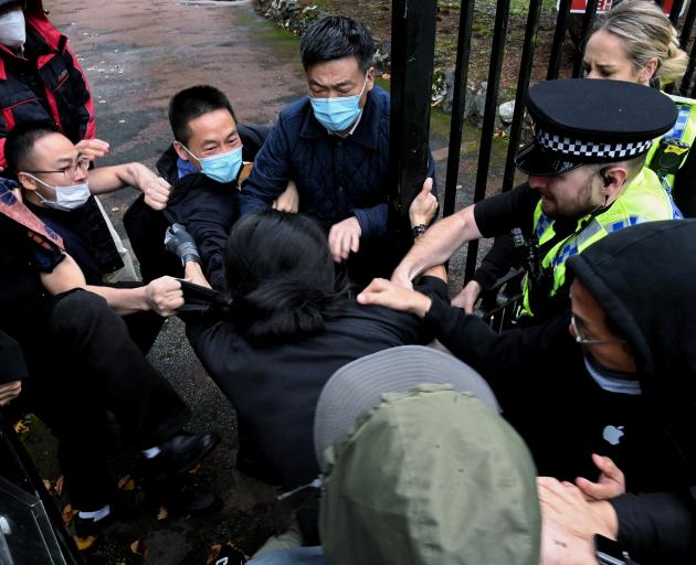 A man is pulled at the gate of the Chinese consulate after a demonstration against China's...
