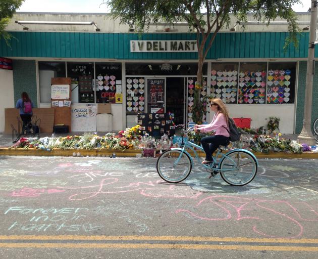 A student bicycles past a makeshift memorial in front of IV Deli Mart in Isla Vista. Photo: Getty...