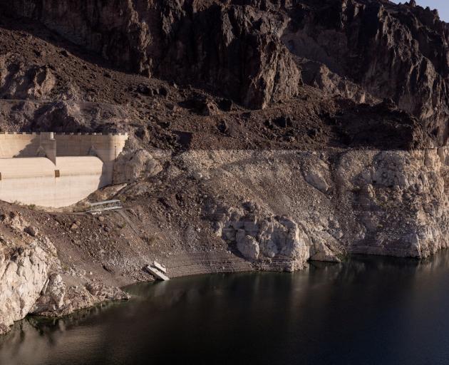A dry spillway at Hoover Dam and stairs ending on a cliff are seen next to the growing ring...