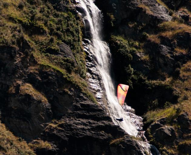 A paraglider flies past Twin Falls near Wanaka on Sunday afternoon. Paragliders took to the skies...
