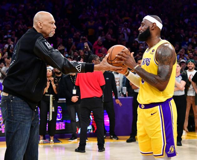 LeBron James (right) takes a ball from Kareem Abdul-Jabbar after breaking the record for all-time...