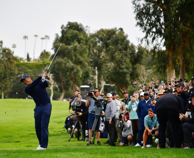 Tiger Woods plays his shot onto the second hole fairway from the rough during the first round of...