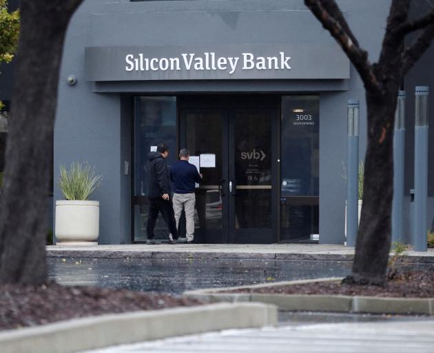 A man puts a sign on the door of the Silicon Valley Bank headquarters in California after the...