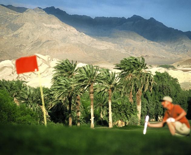 A golfer lines up a putt at Furnace Creek Golf Course, Death Valley.