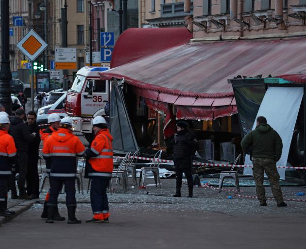 Investigators and members of emergency services work at the site of an explosion in a cafe in...