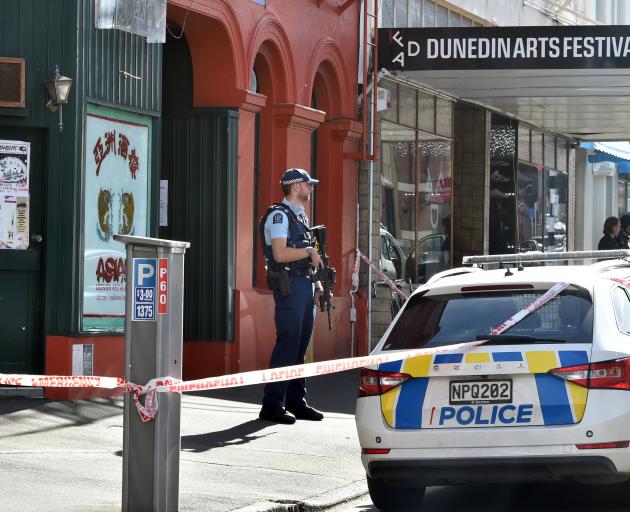 An armed officer stands guard while a scene examination takes place at Yours, a cafe and arts...