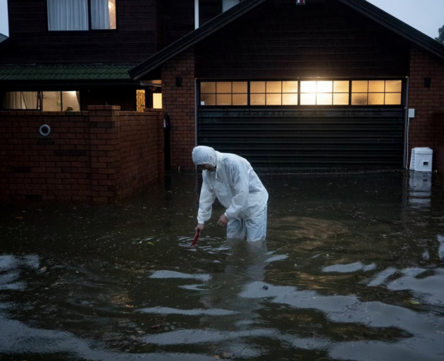 A man tries to clear the drain outside his house in Greenlane during the January 27 flooding....