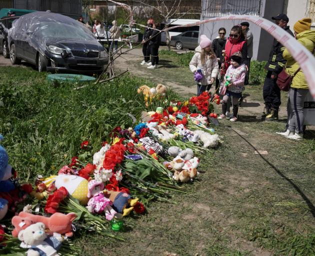 Residents place flowers and toys to pay tribute to civilians killed by a Russian missile strike...