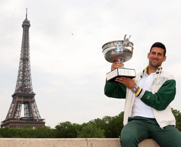Novak Djokovic poses with the French Open trophy after claiming a record 23rd grand slam earlier...