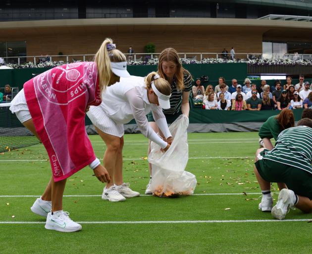 Britain's Katie Boulter and Australia's Daria Saville help to pick up confetti thrown by a Just...