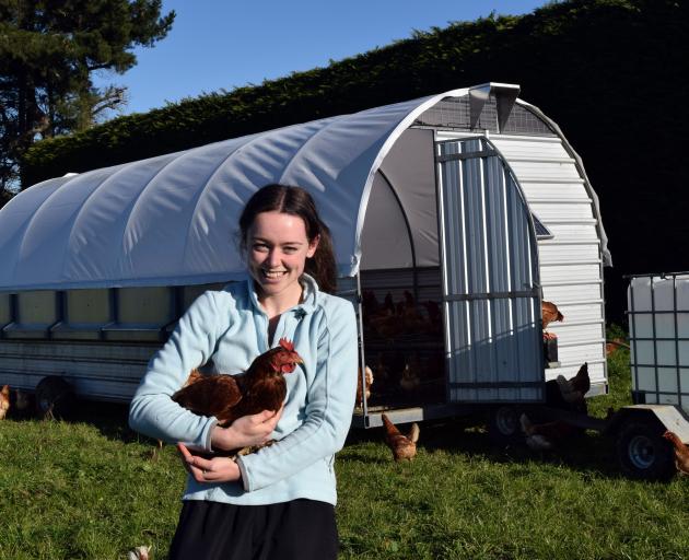 Red Feather Eggs owner Naomi Hanning holds one of her chooks outside a mobile coop on her family...