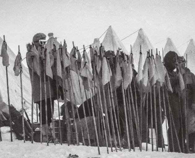 Erebus recovery team members attach coloured flags to bamboo poles ready to mark the location of...
