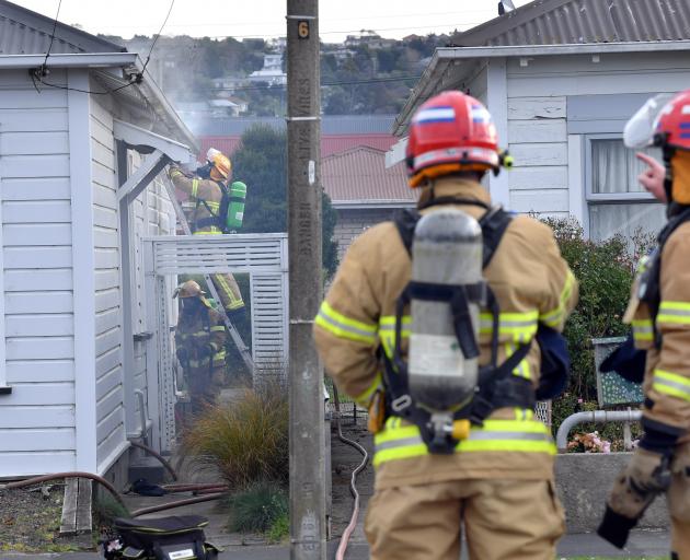 Firefighters worked to extinguish a fire in the wall of a house in Baker St yesterday. Photo:...