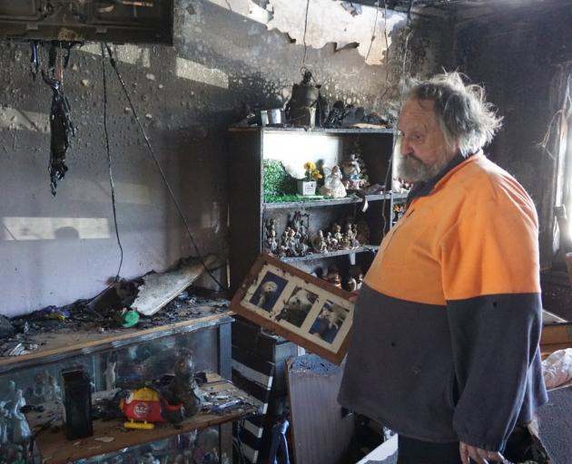 Oamaru man Neville Bryant looks through the remains of his living room after their family home...