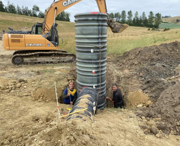 West Otago farmer Al Body (right) and his son Jack (then 15) compact soil around a detainment...