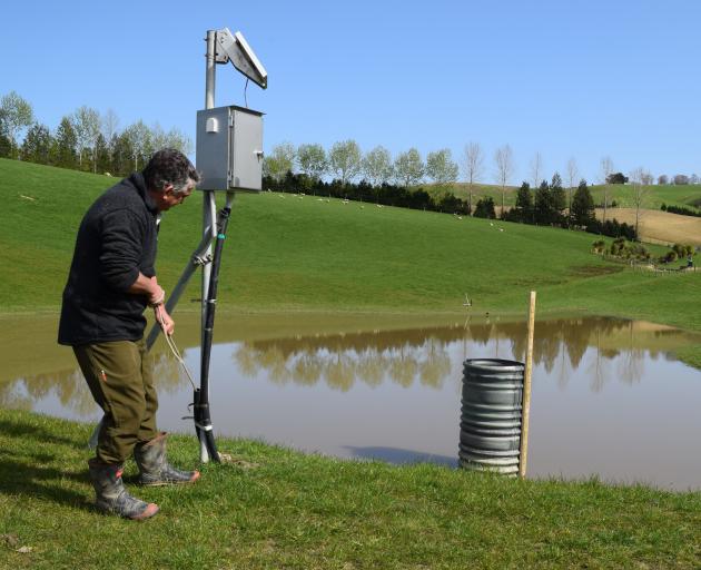 Sheep and beef farmer Al Body pulls a rope to open a slide valve on a detainment bund to release...