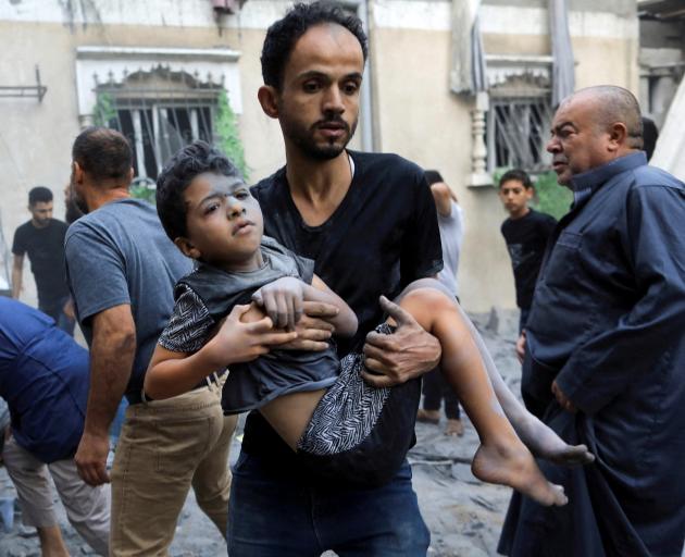 A man carries a wounded child at the site of an Israeli strike in Khan Younis in the southern...