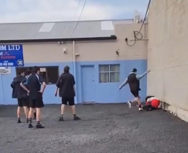 King’s High School students watch while a student from another school is kicked on the ground....