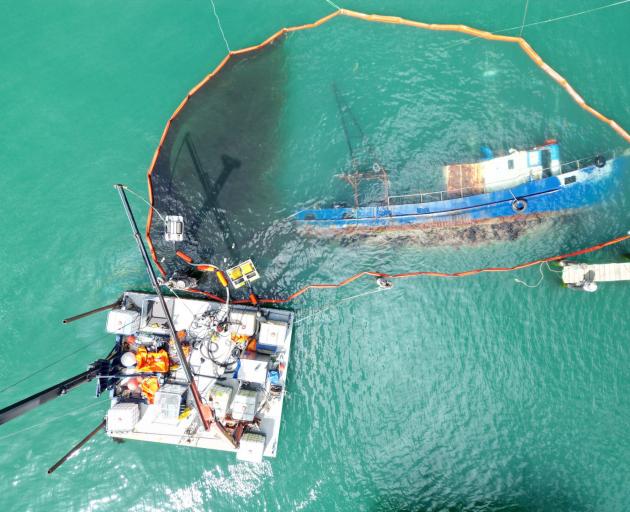 Before: Two mechanical skimmers within the boom work to remove fuel that leaked from the sunken...