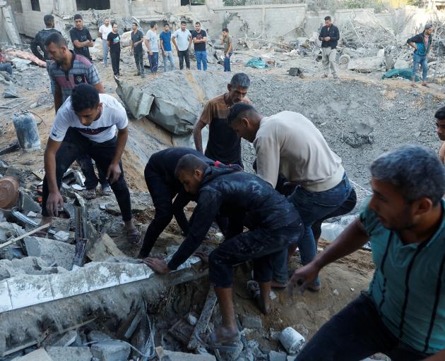 Palestinians work on clearing the destruction of a house in the aftermath of a strike amid the...