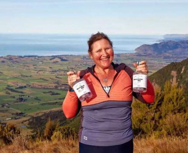 Justine Schroder standing on Mt Fyffe with her award winning gins. Photo: Supplied