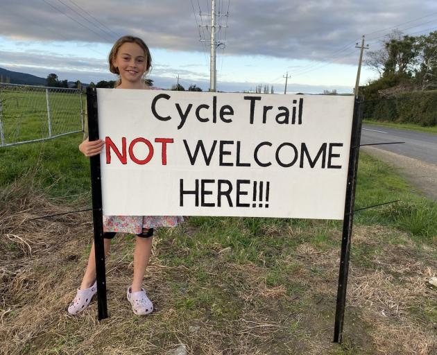 Poppy Sutherland, 10, stands by a sign at the entrance of her home opposing the route of a...
