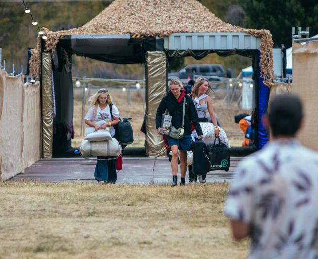 Festival-goers haul their camping gear through the main entrance of the Rhythm & Alps music...