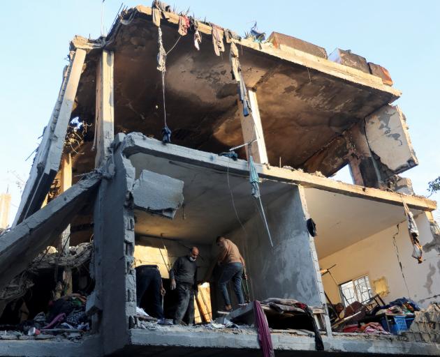 People search for casualties at the site at the site of Israeli strikes on houses, in Rafah,...