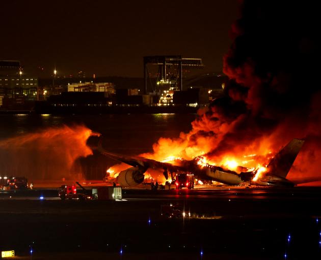 Firefighters work at Haneda International Airport after Japan Airlines' A350 airplane caught on...