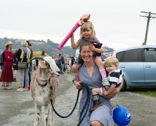 Alice Perry, of Weston, carries Ella, 3, and Ollie Harvey, 1, while wrangling Ralph the goat, 4,...
