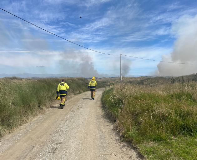 Firefighters approach the scene of the blaze that is spreading the grassy dunes at Oreti Beach....