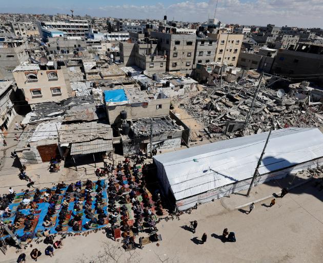 Palestinians perform first Friday prayers during Ramadan near the ruins of a destroyed mosque,...