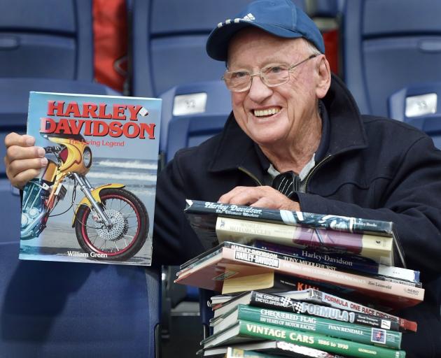 Dunedin resident David Ferguson holds his huge haul of books about Harley Davidsons, Formula One...