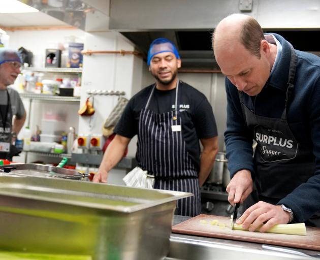 Prince William helps out in the kitchen during a visit to Surplus to Supper, a food...