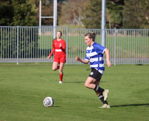Wyndham Town player Freya Bols collects a pass, dribbles the ball about 15m and then boots it...