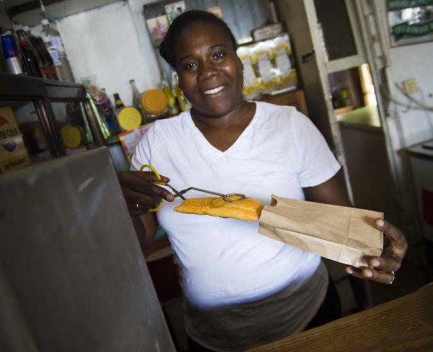 A local woman sells a patty that is a popular local snack (similar to a pasty with various...