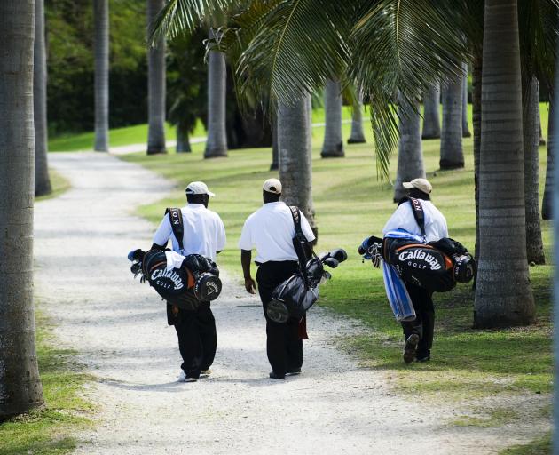 Three caddies head for the green at Half Moon golf course. PHOTO: PAUL MARSHALL