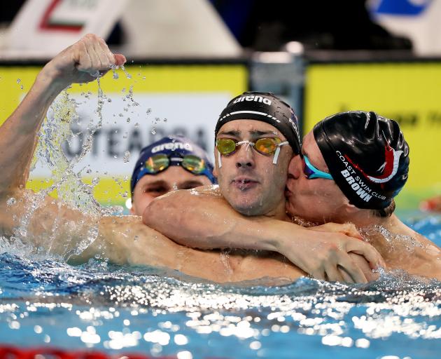 Kane Follows (centre) celebrates with Lewis Clareburt (left) and Sam Brown (right) after swimming...