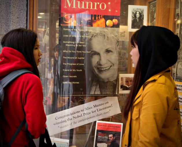 Customers look at a window display congratulating Canadian author Alice Munro at her own...