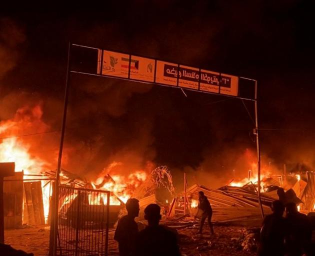 Fire rages following an Israeli strike on an area designated for displaced Palestinians, in Rafah...
