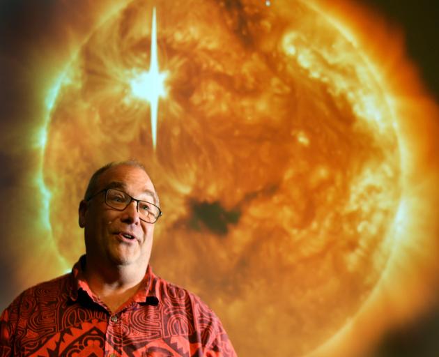 University of Otago physics Prof Craig Rodger in front of an image of a coronal mass ejection ...